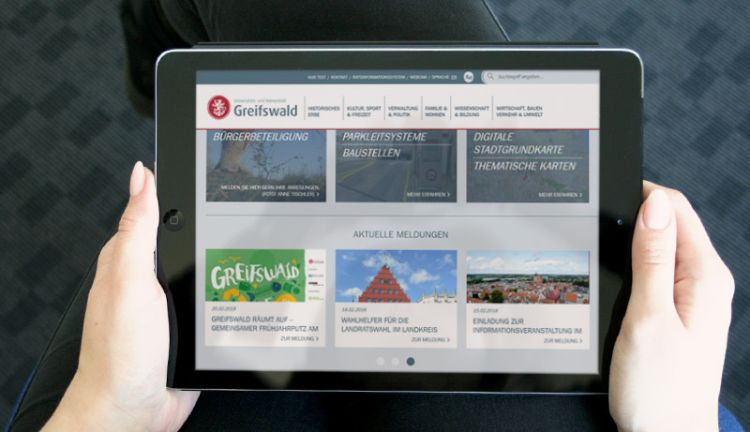 Hansestadt Greifswald - Klare Informationsstruktur Website der Hansestadt Greifswald auf einem Tablet, in Händen gehalten