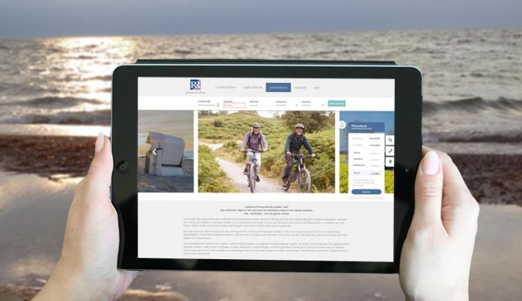 Direktbuchung ist intelligent eingebunden Buchungsseite der R&R Hotels und Villen GbR auf einem Tablet in der Hand am Strand von Baabe Ruegen