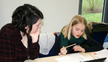 Zwei junge Mädchen sitzen am Schreibtisch vor einem Blatt Papier