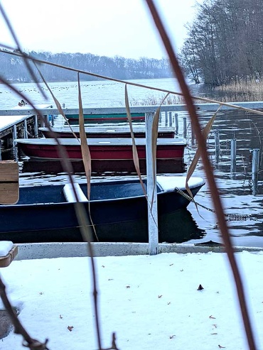 Ruderboote am schneebeckten Bootsteg am Neumühler See