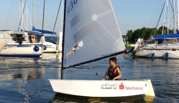 Junge segelt im Segelboot Optimist